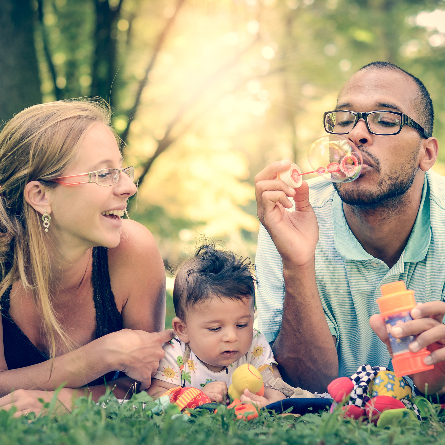 Parents blowing bubbles with young baby